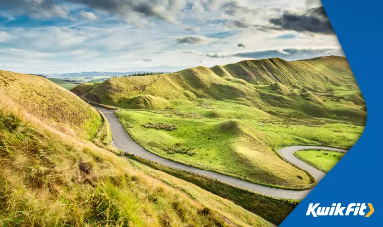 A winding road through the green peaks of Snake Pass Summit in the Peak District.