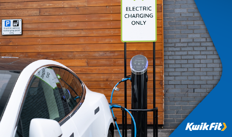 White car parked up using an electric car charger.