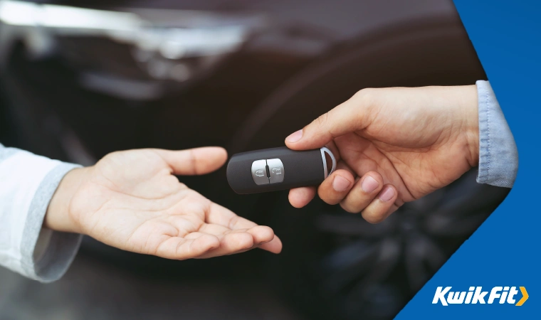 Car salesman passing over keys to a customer.