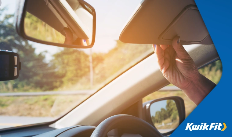 A driver using a driver's visor to avoid getting blinded by low sun.