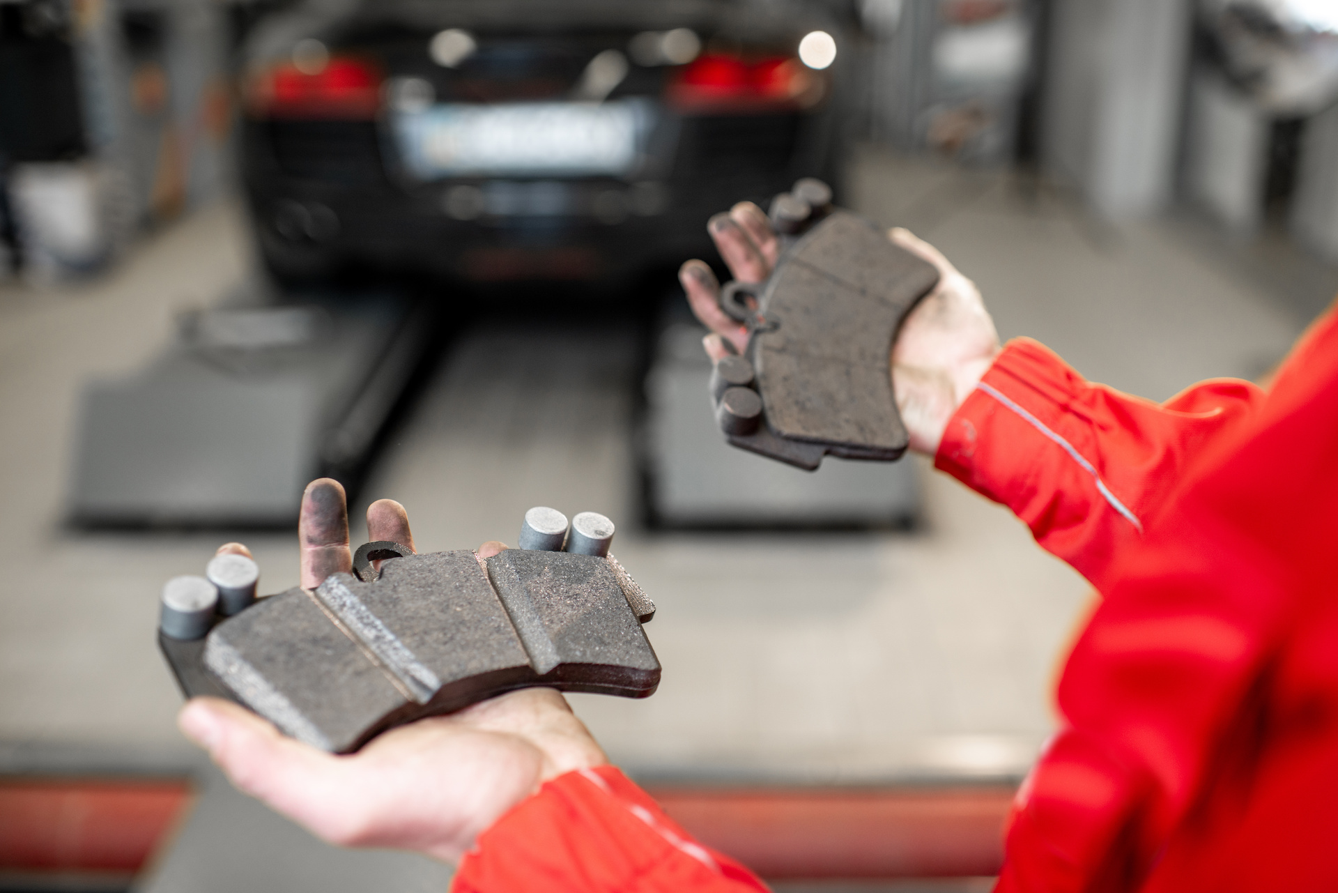 Technician holding dirty brake pads.