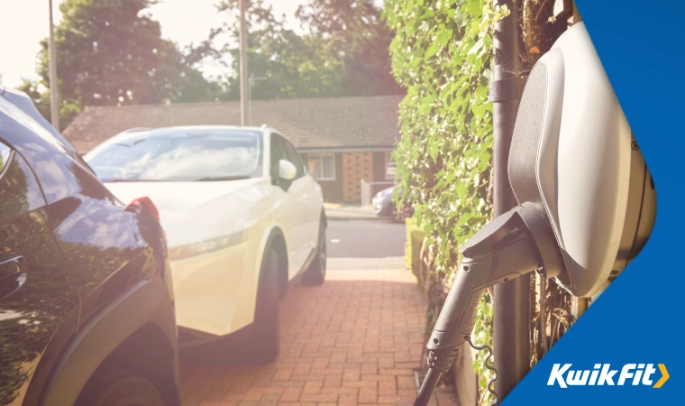  A white electric vehicle plugged in on a typical UK driveway.