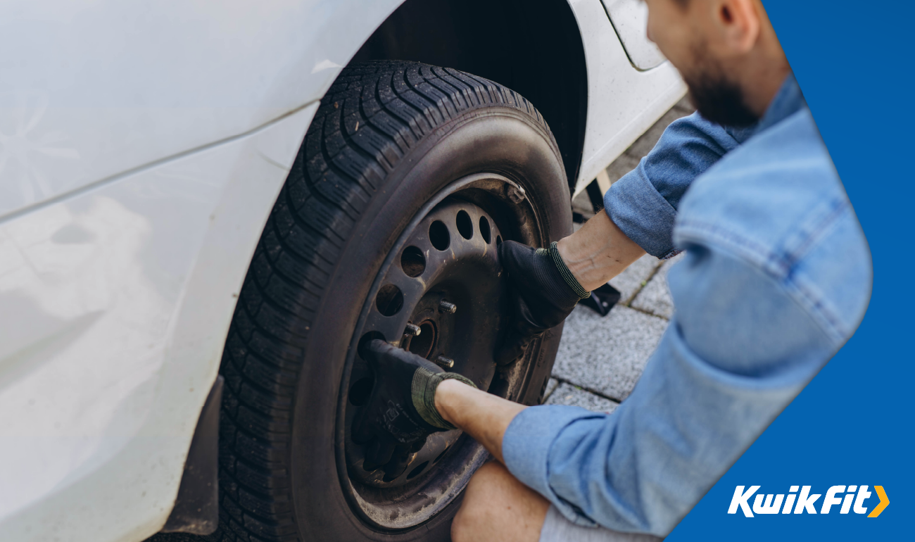 Person with gloves on changing a tyre.