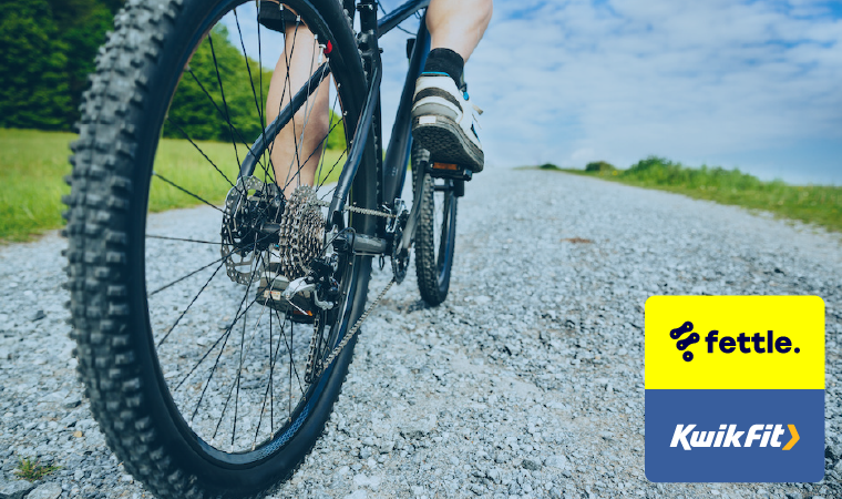 Person cycling on a rubble path surrounded by green grass and trees.