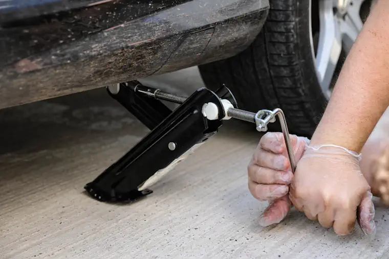 Person raising a car with a jack.