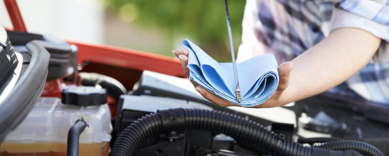 Car owner checking their vehicles oil level using a dipstick