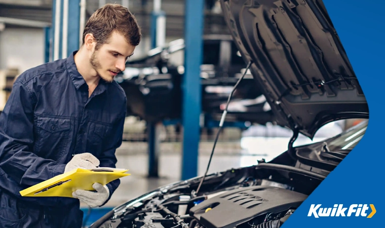 A mechanic going through an MOT checklist to assess a car's safety.