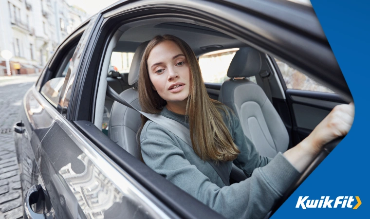 Woman checks side mirror while reversing car.