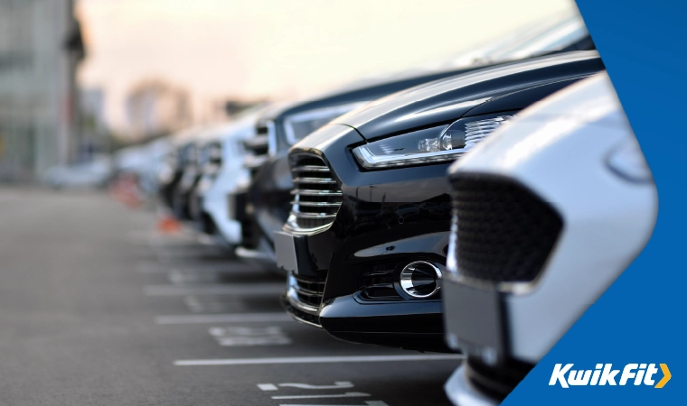 A row of cars in a busy car park.