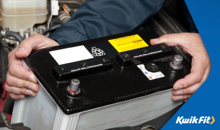 Mechanic removing an old battery from a car.