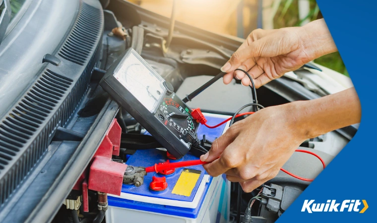 Person opening their car bonnet and using a battery tester to ensure their battery carries on working effectively. to