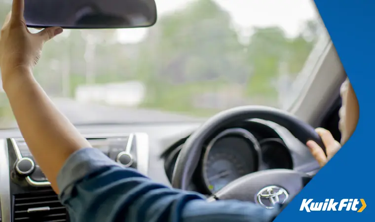 Person adjusting rear view mirror.