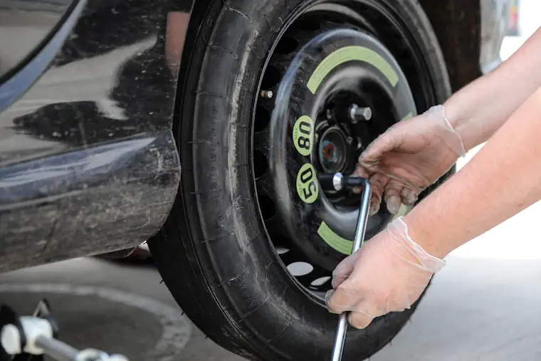 Tightening car wheel nuts with a wrench.