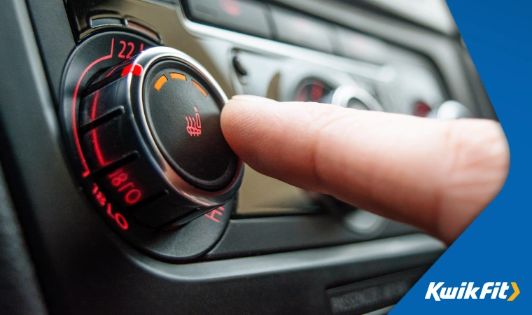 Close up of a hand turning on the heating in a car.